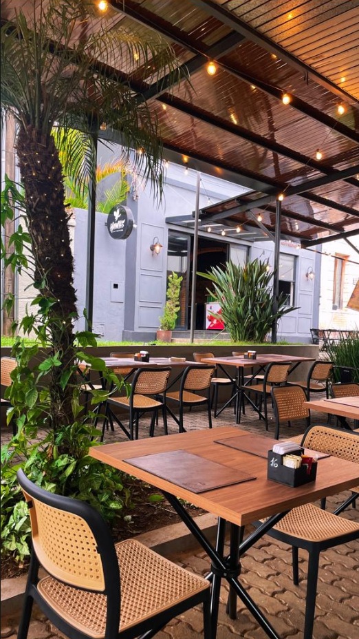 Área externa do Hawks BBQ com palmeiras e ambiente ao ar livre